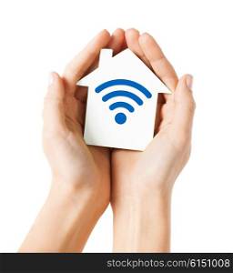 people, internet connection, security, alarm and technology concept - close up of hands holding house with radio or wifi wave signal icon