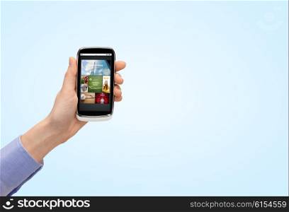 people, internet, technology and media concept - close up of woman hand with smartphone with web pages on screen