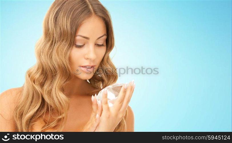 people, jewelry, luxury and beauty concept - woman holding big diamond over blue background