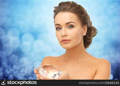 people, jewelry, luxury and beauty concept - woman showing big diamond over blue lights