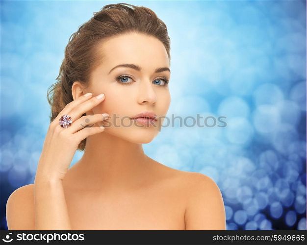 people, jewelry, luxury and glamour concept - woman wearing diamond ring over blue lights background
