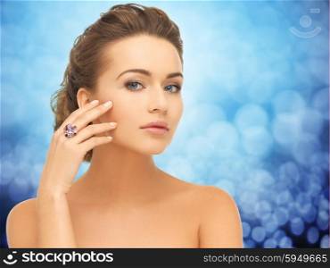 people, jewelry, luxury and glamour concept - woman wearing diamond ring over blue lights background