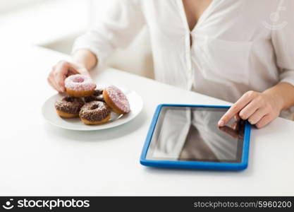 people, junk food, diet, technology and unhealthy eating concept - close up of hands with tablet pc computer and donuts counting calories and sitting at table at home