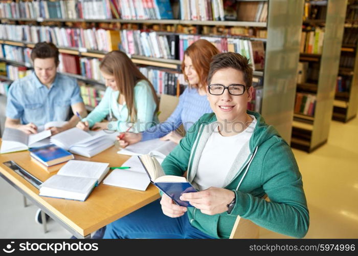 people, knowledge, education and school concept - group of happy students reading books and preparing to exam in library