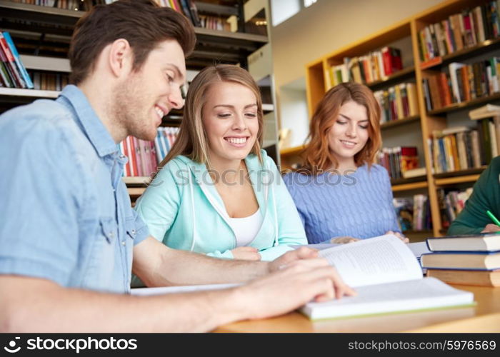 people, knowledge, education and school concept - group of happy students reading books and preparing to exam in library