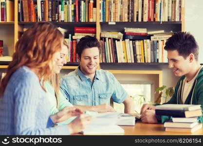 people, knowledge, education and school concept - group of happy students reading books and preparing to exam in library