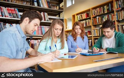 people, knowledge, education and school concept - group of happy students with tablet pc computers writing to notebooks in library