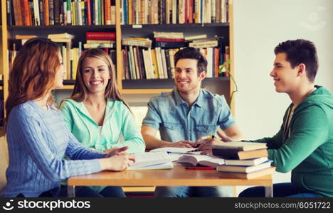 people, knowledge, education and school concept - group of happy students with books talking and preparing to exam in library