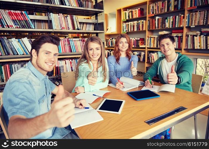 people, knowledge, education and school concept - group of happy students with tablet pc computers showing thumbs up in library