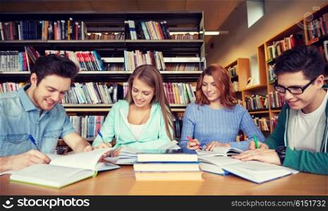 people, knowledge, education and school concept - group of happy students writing to notebooks in library