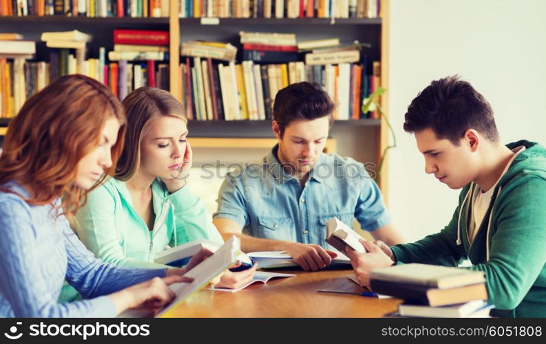 people, knowledge, education and school concept - group of students reading books and preparing to exam in library