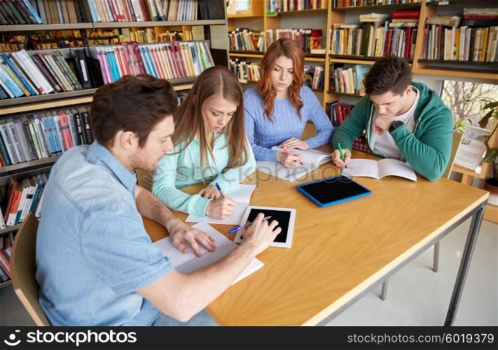 people, knowledge, education and school concept - group of students with tablet pc computers writing to notebooks in library