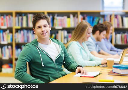 people, knowledge, education and school concept - happy student boy reading books in library