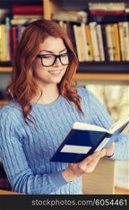 people, knowledge, education and school concept - happy student girl in eyeglasses reading book in library