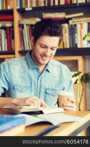 people, knowledge, education and school concept - happy student reading book and drinking coffee in library