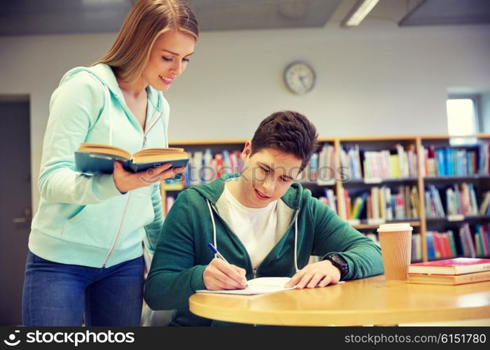 people, knowledge, education and school concept - happy students with book preparing to exams in library