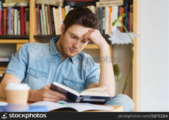 people, knowledge, education and school concept - male student reading book in library