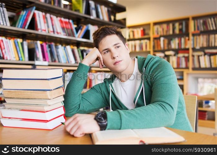 people, knowledge, education, literature and school concept - bored student or young man with books dreaming in library