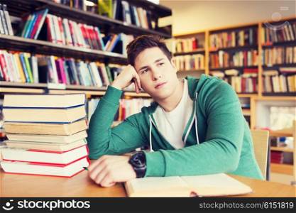 people, knowledge, education, literature and school concept - bored student or young man with books dreaming in library
