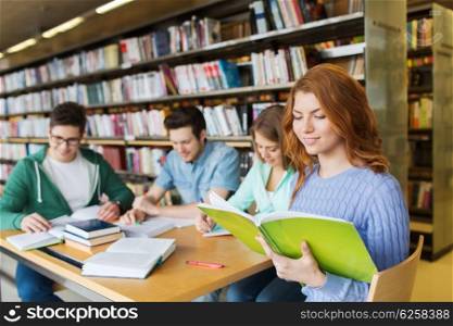 people, knowledge, education, literature and school concept - happy students reading books and preparing to exams in library
