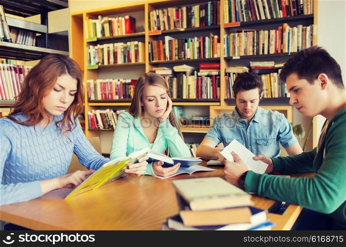 people, knowledge, education, literature and school concept - students reading books and preparing to exams in library