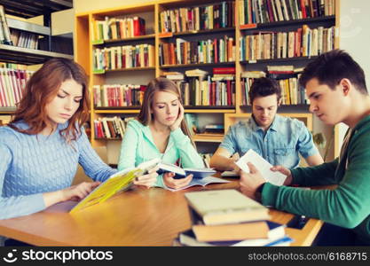 people, knowledge, education, literature and school concept - students reading books and preparing to exams in library