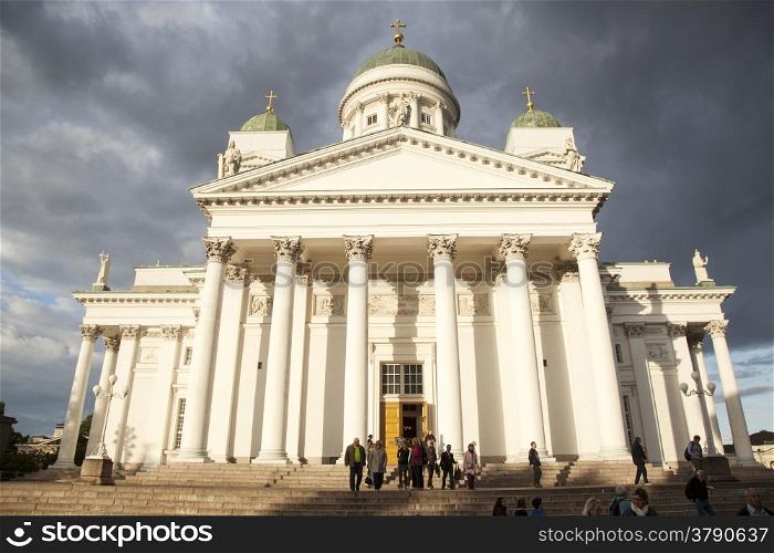 people leaving helsinki cathedral in the evening under threatening sky