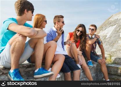 people, leisure and communication concept - group of happy teenage friends talking outdoors