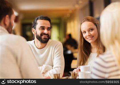 people, leisure and communication concept - happy friends meeting and drinking tea or coffee at cafe