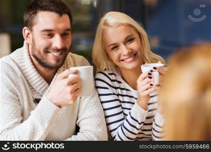 people, leisure and communication concept - happy friends meeting and drinking tea or coffee at cafe