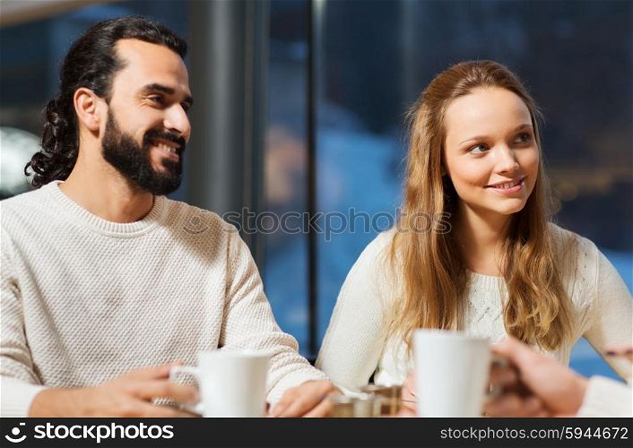 people, leisure and communication concept - happy friends or couple meeting and drinking tea or coffee at cafe