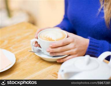 people, leisure and drink concept - close up of woman with coffee cup at cafe
