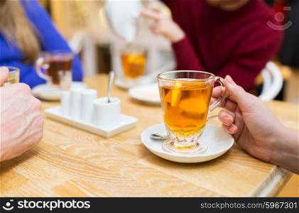 people, leisure and drinks concept - close up of female hand with cup of lemon tea lemon at cafe