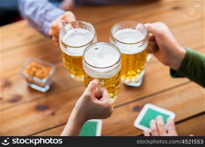 people, leisure and drinks concept - close up of hands clinking beer mugs at bar or pub