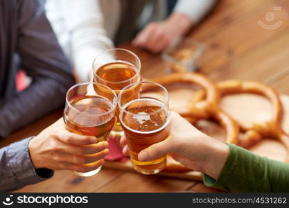 people, leisure and drinks concept - close up of male hands clinking beer glasses and pretzels at bar or pub