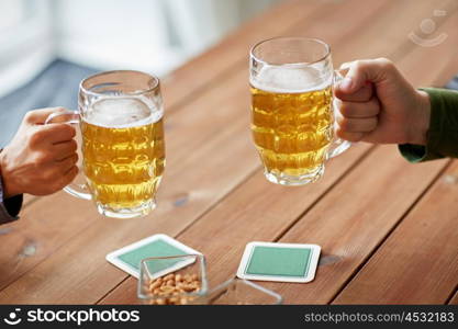 people, leisure and drinks concept - close up of male hands with beer mugs and peanuts at bar or pub