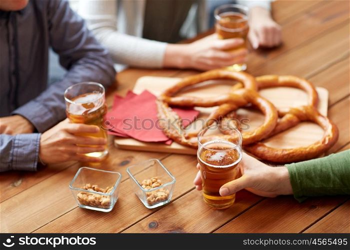 people, leisure and drinks concept - close up of male hands with beer glasses, pretzels and peanuts at bar or pub