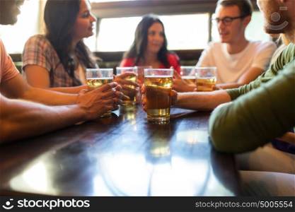 people, leisure and drinks concept - friends drinking beer and at bar or pub. friends drinking beer at bar or pub