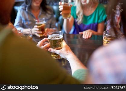 people, leisure and drinks concept - friends drinking beer and at bar or pub. friends drinking beer at bar or pub