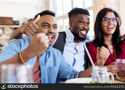 people, leisure and entertainment concept - happy fans or friends celebrating victory at bar or restaurant. happy fans or friends at bar or restaurant
