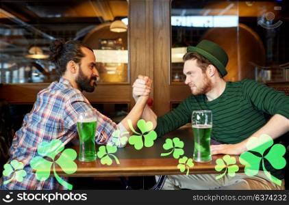 people, leisure and entertainment concept - male friends drinking draft green beer and arm wrestling at bar or pub. men drinking green beer and arm wrestling at pub