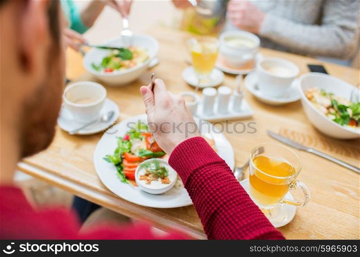 people, leisure and food concept - close up friends having dinner and eating at restaurant