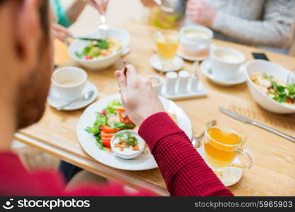 people, leisure and food concept - close up friends having dinner and eating at restaurant