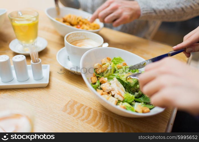 people, leisure and food concept - close up friends having dinner and eating at restaurant