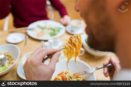 people, leisure and food concept - close up man eating pasta for dinner at restaurant or home