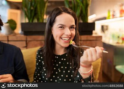 people, leisure and food concept - happy young woman eating at restaurant