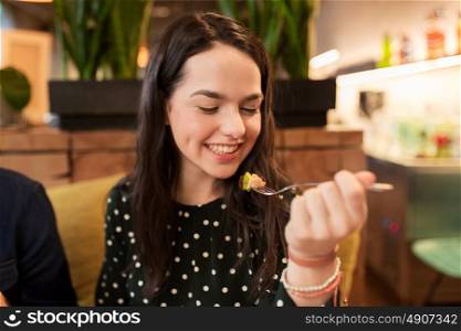 people, leisure and food concept - happy young woman eating at restaurant. happy young woman eating at restaurant