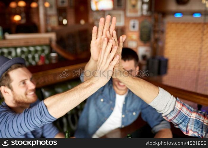 people, leisure and friendship concept - close up of happy male friends drinking beer at bar or pub and making high five