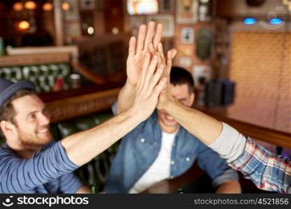 people, leisure and friendship concept - close up of happy male friends drinking beer at bar or pub and making high five