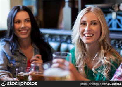 people, leisure and friendship concept - happy women meeting with friends and drinking beer at bar or pub